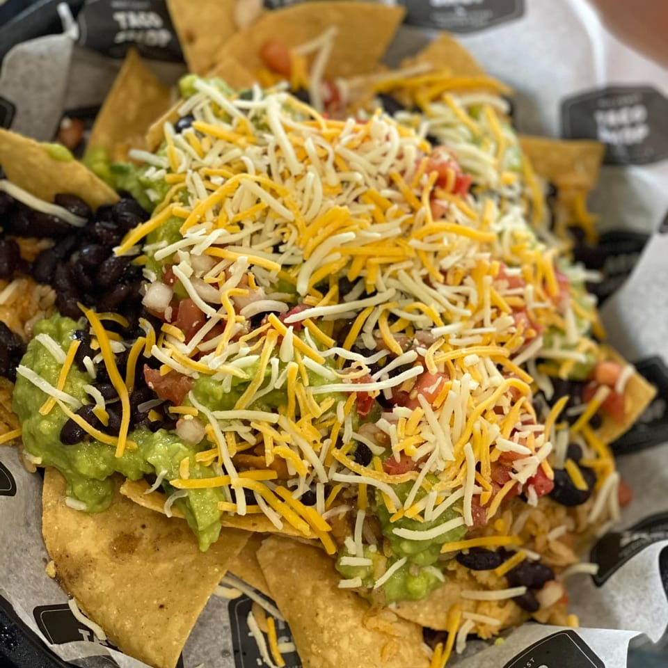 Oscar's Taco Shop nachos with guacamole, black beans, pico de gallo, and shredded cheese.