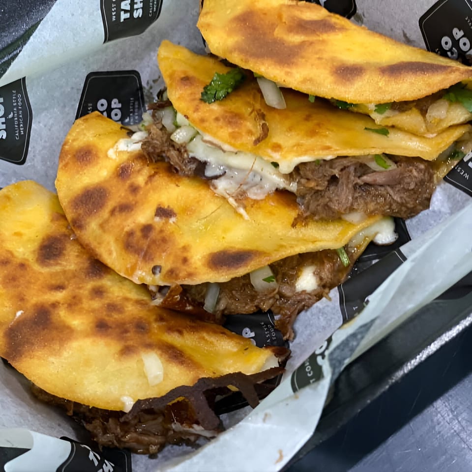 Three golden-brown Oscar's Taco Shop birria tacos filled with meat, cheese, onions, and cilantro.